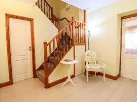 A hallway with a staircase and chair at Llwyn Derw in Talybont