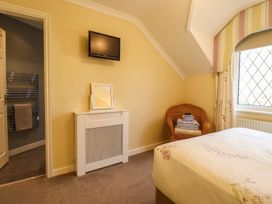 A bedroom with a bed, TV, chair and towels at Llwyn Derw in Talybont