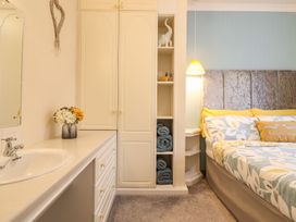 A bedroom with a bed, wardrobe, mirror, and sink at Llwyn Derw in Talybont