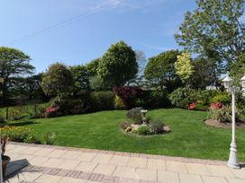 A garden with flower beds and a birdbath at Llwyn Derw in Talybont