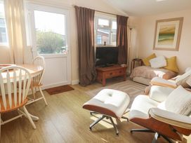 A living room with a sofa and dining area at Chalet 225 in Tregolds near St Merryn