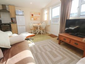 A living room with a sofa and dining area at Chalet 225 Tregolds near St Merryn