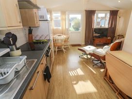 A kitchen with a dining area and television at Chalet 225 Tregolds near St Merryn