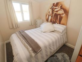 A bedroom with a bed and artwork at Chalet 225 Tregolds near St Merryn