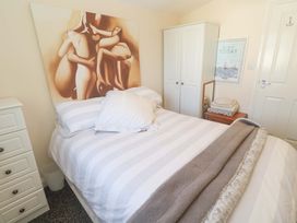 A bedroom with a striped bed and wardrobe at Chalet 225 Tregolds near St Merryn