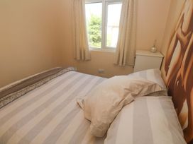 A bedroom with a bed and window at Chalet 225 in Tregolds near St Merryn