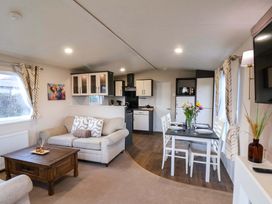 A living room with a dining area and kitchen cabinets at Rosefinch Cabin Scarborough