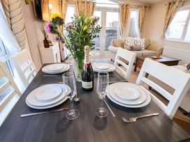 A dining table with plates and a champagne bottle at Rosefinch Cabin Scarborough