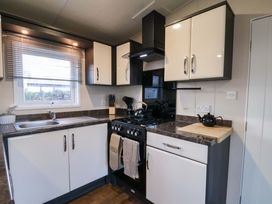 A kitchen with cabinets, sink, and stove at Rosefinch Cabin Scarborough