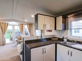 A kitchen area with cabinets and sink overlooking a living room at Rosefinch Cabin Scarborough