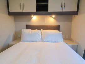 A bedroom with a bed and wall cabinets at Rosefinch Cabin in Scarborough