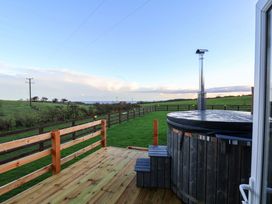 An outdoor area with a hot tub and wooden deck at Rosefinch Cabin in Scarborough