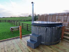 A hot tub with steps and stove in a grassy area at Rosefinch Cabin in Scarborough