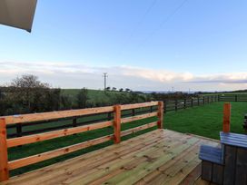 An outdoor deck with a wooden railing and grass at Rosefinch Cabin in Scarborough