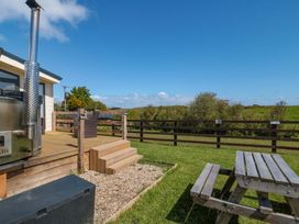 An outdoor seating area with a bench and gravel at Rosefinch Cabin Staintondale near Scarborough
