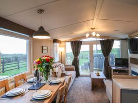 A living room with a dining area and windows at Swift Cabin Scarborough