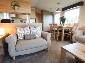 A living room with a sofa and dining area at Swift Cabin in Scarborough