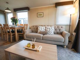 A living room with a sofa and dining area at Swift Cabin in Scarborough