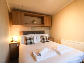 A bedroom with a bed and shelves at Swift Cabin in Scarborough