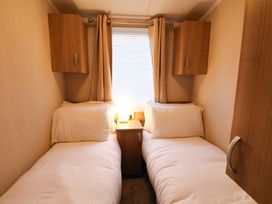A bedroom with twin beds and a lamp at Swift Cabin in Scarborough