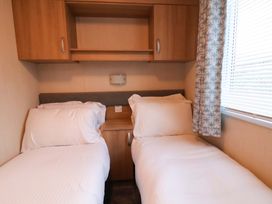 A bedroom with two beds and a shelf at Swift Cabin in Scarborough