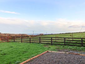 A garden with grass and a fenced area at Swift Cabin in Scarborough