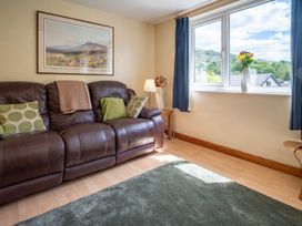 A living room with a sofa, cushions, lamp, and window at Oaks Lodge Cottage in Ambleside