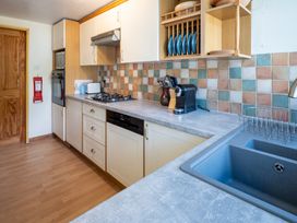 A kitchen with cabinets, sink, stove, and appliances at Oaks Lodge Cottage in Ambleside