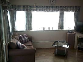 A living room with a clock and sofa at Coopers Beach Holiday Park - Holiday Accommodation 3999 Mersea Island