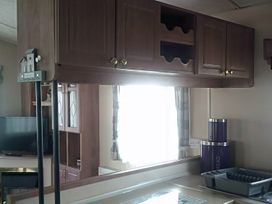 A kitchen with cabinets and a television at Coopers Beach Holiday Park - Holiday Accommodation 3999 Mersea Island