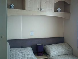 A bedroom with two beds, a lamp, and decorative items at Coopers Beach Holiday Park - Holiday Accommodation 3999, Mersea Island