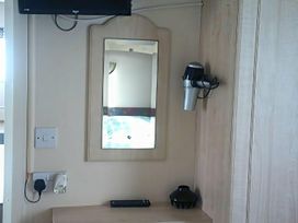 A bedroom with a mirror and hair dryer at Coopers Beach Holiday Park - Holiday Accommodation 3999 Mersea Island