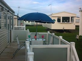 An outdoor seating area with a table and umbrella at Coopers Beach Holiday Park - Holiday Accommodation 3999, Mersea Island