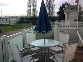 An outdoor patio with a table and chairs at Coopers Beach Holiday Park - Holiday Accommodation 3999 Mersea Island