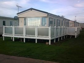 A caravan with decking at Coopers Beach Holiday Park - Holiday Accommodation 3999 Mersea Island