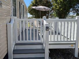 A deck with railing, steps, and an umbrella at Coopers Beach Holiday Park - Holiday Accommodation 6404 Mersea Island