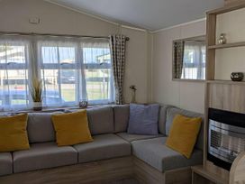 A living room with a sofa and window at Coopers Beach Holiday Park - Holiday Accommodation 6404 Mersea Island