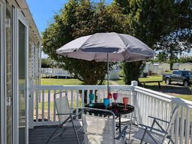 An outdoor area with a table and chairs under an umbrella at Coopers Beach Holiday Park - Holiday Accommodation 6404 Mersea Island
