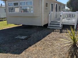 An outdoor area with a static caravan and deck at Coopers Beach Holiday Park - Holiday Accommodation 6404 Mersea Island