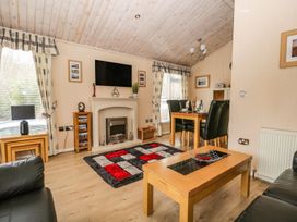 A living room with a coffee table and a television at Kingfisher Lodge Windermere