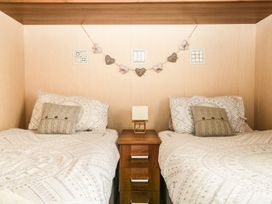 A bedroom with two beds and a nightstand at Kingfisher Lodge Windermere