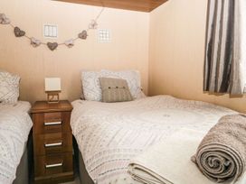 A bedroom with two beds and a bedside table at Kingfisher Lodge in Windermere