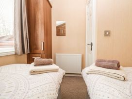 A bedroom with two beds and a wardrobe at Kingfisher Lodge in Windermere