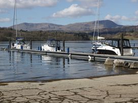 A marina with boats docked and mountains in the background at Kingfisher Lodge Windermere