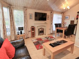 A living room with a fireplace and dining area at Kingfisher Lodge Grasmere 33 White Cross Bay near Windermere