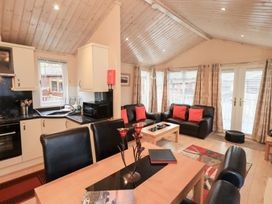A living room with kitchen area and dining table at Kingfisher Lodge Grasmere 33, White Cross Bay near Windermere