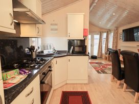 A kitchen with a dining area and appliances at Kingfisher Lodge Grasmere 33 White Cross Bay near Windermere