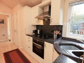A kitchen with cabinets and appliances at Kingfisher Lodge Grasmere 33, White Cross Bay near Windermere