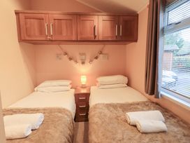 A bedroom with twin beds and a lamp at Kingfisher Lodge Grasmere 33, White Cross Bay near Windermere