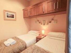 A bedroom with two beds and bedside table at Kingfisher Lodge, Grasmere 33, White Cross Bay near Windermere